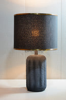 Modern black resin table lamp with elegant silhouette and fabric shade, creating warm ambient lighting for bedrooms, living rooms, and contemporary interiors.