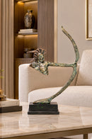 Brown resin bow sculpture displayed on a light stone entryway console beneath a round wall mirror.