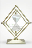 Clear glass and gold cubic hourglass arranged on a wooden sideboard beside contemporary decor pieces.