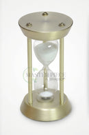 Clear glass sand timer with gold detailing arranged on a decorative tray in a modern living room.