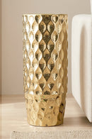Golden dotted metal vase displayed on a marble console table in a luxurious living room.
