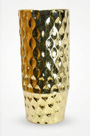 Large dotted golden vase styled beside an accent chair in an elegant living room corner.
