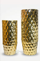 Medium golden metal vase arranged on a dining room sideboard with modern decorative accessories.