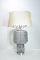 Shop the Brassco Double Grey Glass Table Lamp with premium grey glass construction, elegant fabric shade, E27 bulb compatibility, and warm ambient lighting. Perfect for bedrooms, living rooms, hotels, and luxury interiors.