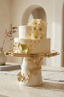 White and gold cake tray displayed on a marble dining table with elegant dinnerware.